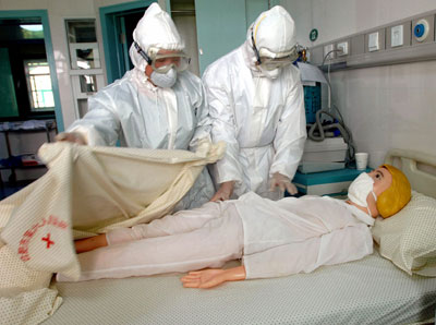 Nurses wearing protective clothes take care of a mock patient, a doll, during a bird flu drill at a hospital in Hefei, east China's Anhui province, August 17, 2006.