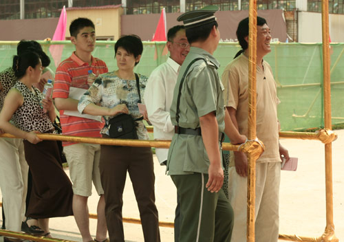 A security man talks with residents at the venue for a vote on demolishment and reconstruction of old buildings in Juixiaqiao Sub-district in Beijing, June 9, 2007. Local government and the real estate developer jointly organize the vote on Saturday to see if majority residents of over 5000 families accept the new compensation policy after failed attempts to reach an agreement through other ways. Both notary officials and supervisors are invited to monitor the vote that runs from 9 a.m. to 9 p.m. at six ballot booths. [Sun Yuqing/m.ming7.cn]