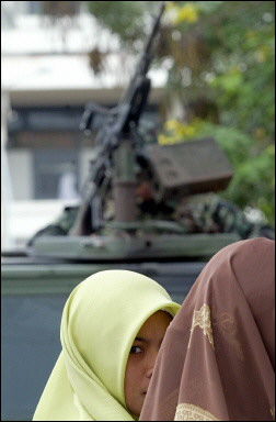 Muslim women stand next to a military vehicle outside a school in Pattani province southern Thailand. More than half of all schools in one of southern Thailand's most strife-torn provinces have been closed following the murder of two teachers by suspected Islamic militants. [AFP/file] 