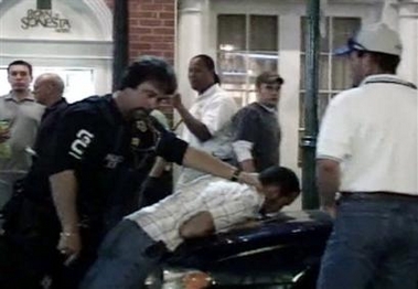 In this image taken from video, a man resembling University of South Florida student Calvin Briles, 21, is seen being held down on a car by unidentified law enforcement personnel in the French Quarter section of New Orleans, Saturday Oct. 8, 2005. Briles told the Bradenton Herald newspaper that he and another USF student Mike Monaghan, 22, witnessed retired teacher Robert Davis being beaten by New Orleans police.