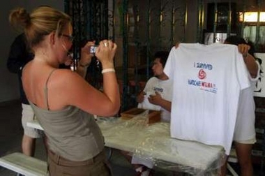 A tourist photographs a 'I survived hurricane Wilma' t-shirt on sale at a storm shelter in Cancun on the Yucatan peninsula as hurricane Wilma approaches October 20, 2005.
