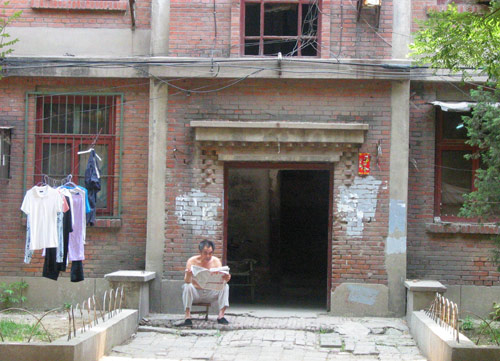 A Chinese man reads newspaper in Juixiaqiao Sub-district in Beijing, June 9, 2007. Local government in Jiuxianqiao and the real estate developer jointly organize the vote on Saturday to see if majority residents of over 5000 families accept the new compensation policy after failed attempts to reach an agreement through other ways. Both notary officials and supervisors are invited to monitor the vote that runs from 9 a.m. to 9 p.m. at six ballot booths. [Sun Yuqing/m.ming7.cn]