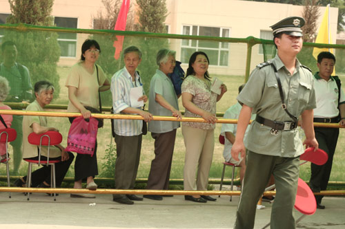 A security man carries a charir at the venue for a vote on demolishment and reconstruction of old buildings in Juixiaqiao Sub-district in Beijing, June 9, 2007. Local government and the real estate developer jointly organize the vote on Saturday to see if majority residents of over 5000 families accept the new compensation policy after failed attempts to reach an agreement through other ways. Both notary officials and supervisors are invited to monitor the vote that runs from 9 a.m. to 9 p.m. at six ballot booths. [Sun Yuqing/m.ming7.cn]
