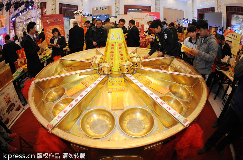 Visitors look at a big copper hot pot during a cooking skill competition in Taiyuan, the capital of North China's Shanxi province, Nov 22 2013. Giant hot pot sparkles in N China
