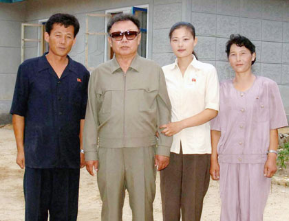 North Korean leader Kim Jong-il (2nd L) poses for a picture with the family of farm manager Yun Ho-jung (L) during an inspection of a stock-breeding centre of the Korean People's Army unit 757, in an unspecified location in North Korea, in this undated photo released by Korea News Service in Tokyo August 14, 2006.