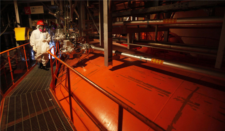 A member of the media, wearing a protective suit and a mask, visits the suppression chamber in the basement of the No 5 reactor building at the Tokyo Electric Power Co's (TEPCO) tsunami-crippled Fukushima Daiichi nuclear power plant in Fukushima prefecture March 10, 2014. Visit to Fukushima nuclear plant on meltdown anniversary
